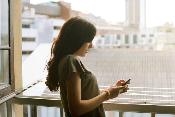 istock young girl using mobile phone at the window 1254630165