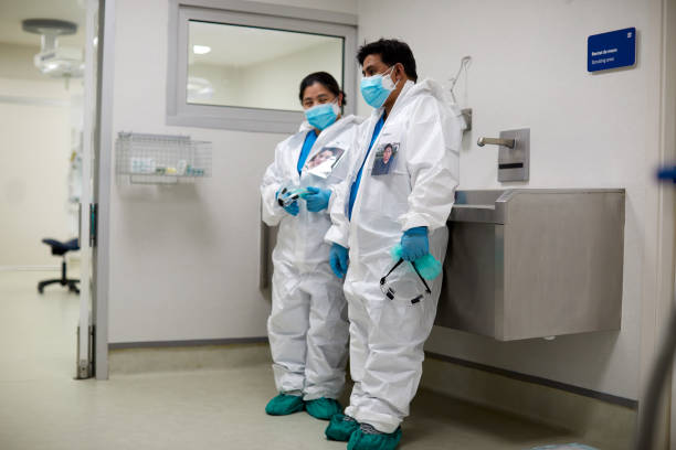 istock Two overworked healthcare workers resting in PPE clothes. 1254631816