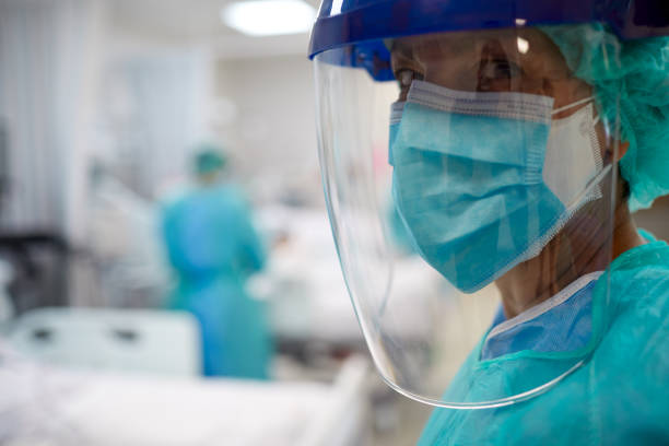 Close up view of a doctor wearing surgical mask and a face shield. Hospital COVID intensive care unit stock pictures, royalty-free photos & images
