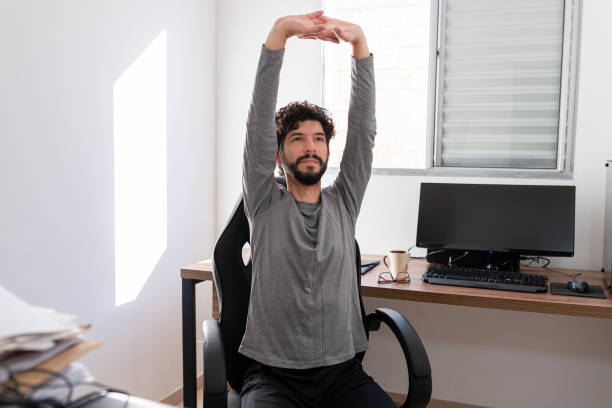 istock Hispanic man doing stretching at home office. Work at home concept 1254639846