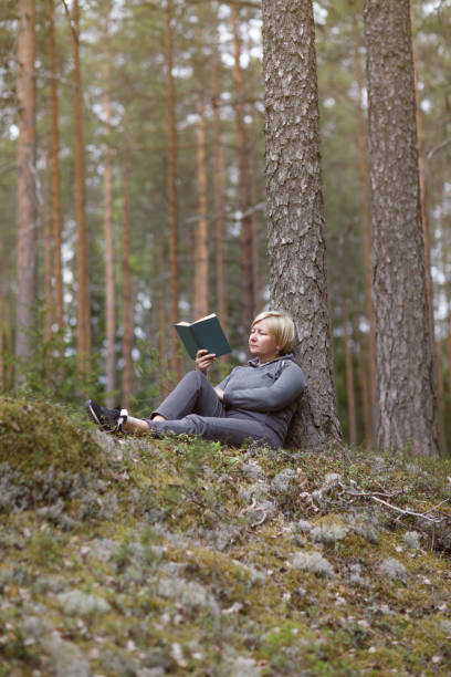 istock girl reading a book in the forest 1254640163