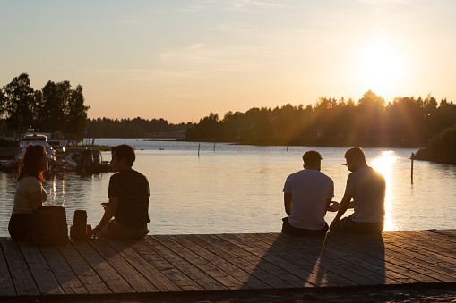 Oulu, Finland - June 2020: people sitting on the waterside, warm evening sunlight