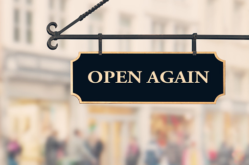 OPEN AGAIN sign against open shop windows background. Restarting business after coronavirus quarantine lockdown. Economy reopening concept.