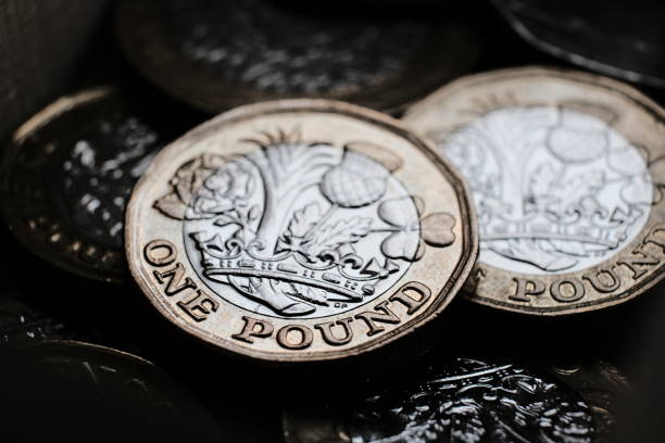 British one pound coins placed on top of each other in the box. Coins have shiny reflections and deep shadows. Macro photo with dramatic shadows. pound sign stock pictures, royalty-free photos & images