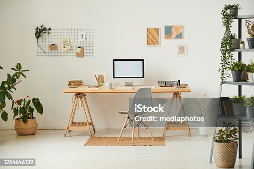 istock Comfortable workplace with potted plants, wall organizer, pictures and computer 1254646139
