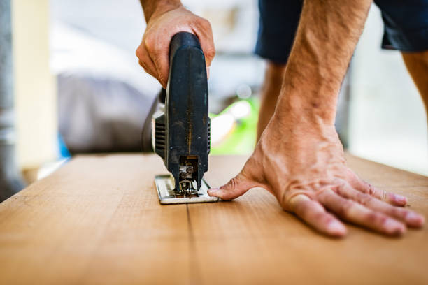 Close-up of a mid adult carpenter cutting wooden plank.