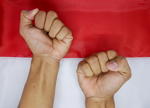 Hands clenched on the Indonesian flag. Symbol of the patriotism and independence day