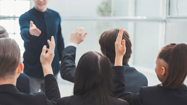 istock rear view. employees ask questions at a business briefing 1254650569