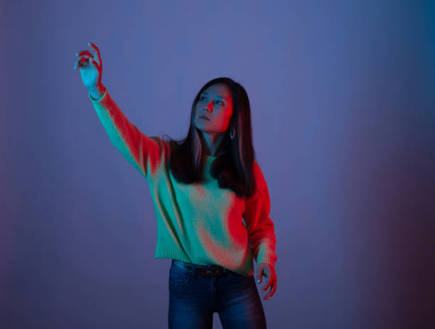 istock Pretty young woman is touching invisible display while standing on purple background 1254650740