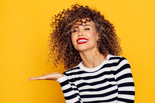 Beautiful woman with curly hair demonstrates your product