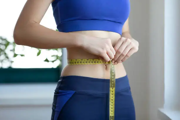 Photo of Unrecognizable young woman measuring her waist