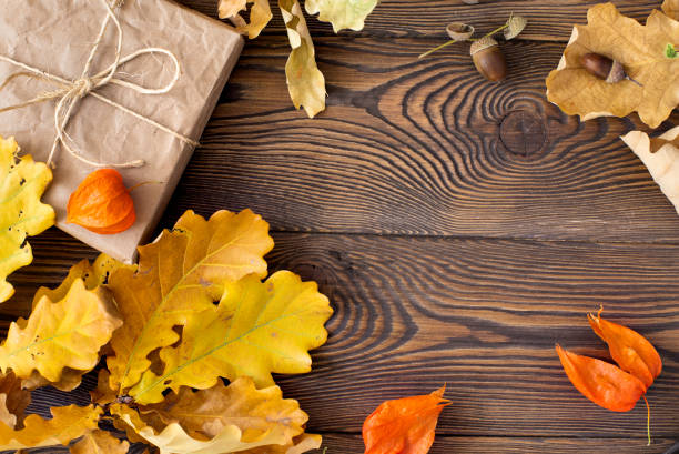 크래프트 페이퍼에 싸여 있는 선물의 최고 전망과 나무 테이블에 오크와 도토리의 노란 잎. 가을 또는 겨울 구성. - 2657 뉴스 사진 이미지