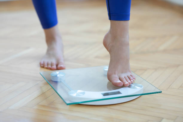 Female feet weighing scale Female feet weighing scale low body fat stock pictures, royalty-free photos & images