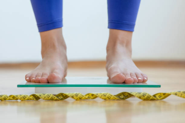 istock Female feet on weighing scale 1254659840