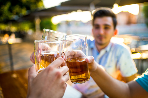 Young men toasting with beer in outdoor pub