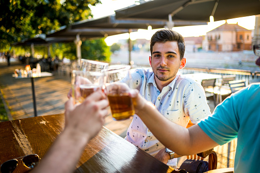 Male friends toasting with beer glasses outdoor