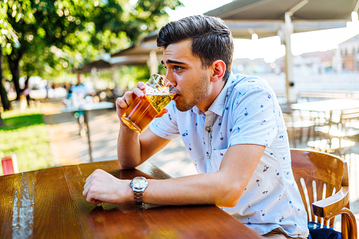 Young caucasian man drinking beer in outdoor pub