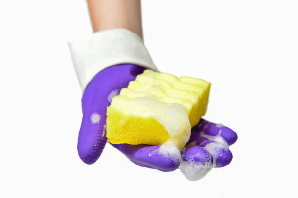istock Hand with gloves squeezes a dishwashing sponge with foam 1254664274