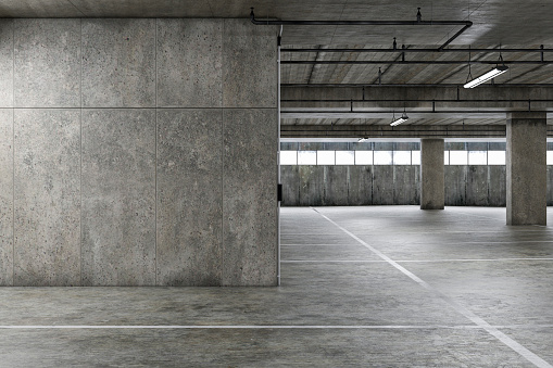 Empty public underground parking lot or garage interior with concrete stripe painted columns and signs.