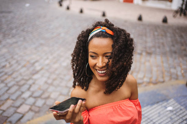 istock Smiling cheerful Hispanic woman recording a voice message while on the move 1254673909
