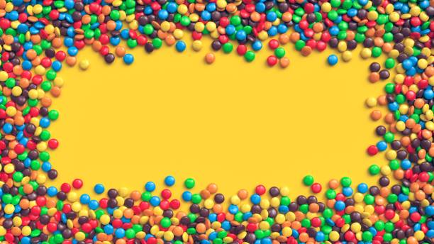 istock Colorful coated chocolate candies frame on yellow background 1254677550