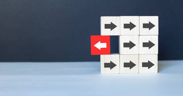istock Wooden block with red arrow facing the opposite direction black arrows, Unique, think different, individual and standing out from the crowd concept 1254678311