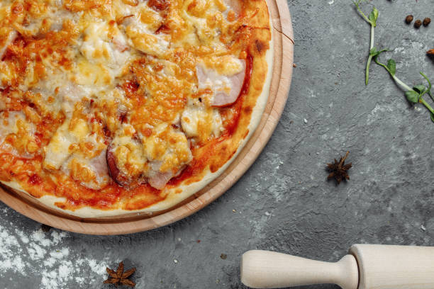 istock pizza with cheese, sauce and ham, bacon, salami on a gray dark background 1254682098