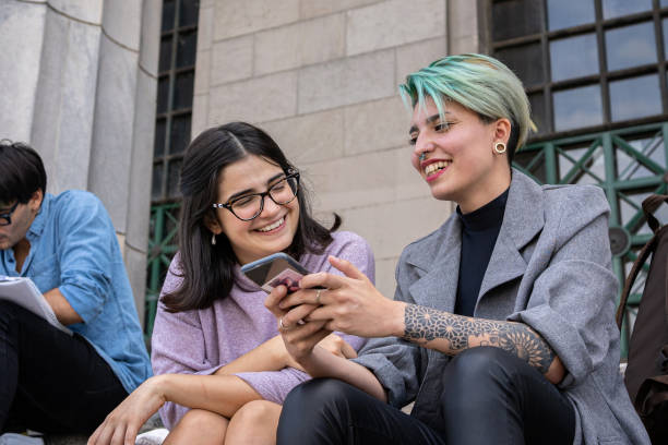 istock Beautiful young students having fun outdoors looking at a mobile phone 1254683917