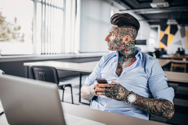 istock Businessman with whole body covered in tattoos using phone in office 1254685221