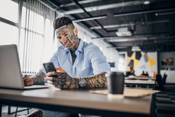 istock Businessman with whole body covered in tattoos using phone in office 1254685332