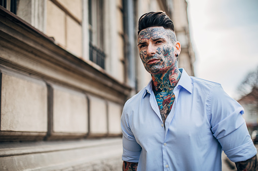 One man, modern man with whole body covered in tattoos, walking on the street.