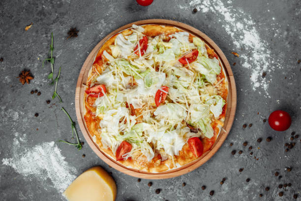 istock Delicious pizza Caesar style with white sauce, chicken, parmesan, egg, cherry tomatoes and fresh lettuce at wooden background 1254687028