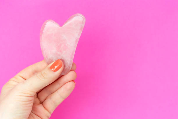 pink quart guasha in woman's hand on background a copy space - quart imagens e fotografias de stock