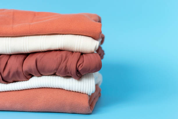 istock Clothes of different colors are folded neatly into stack on blue background 1254688833