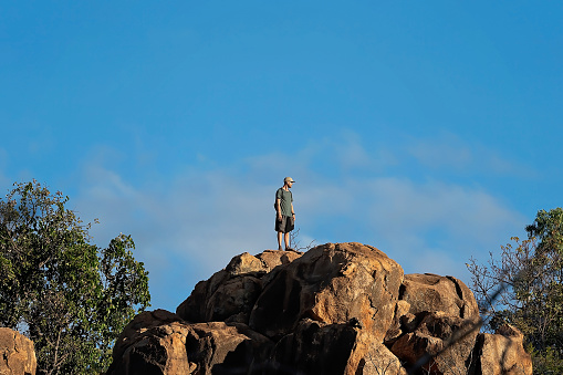 Undara Volcanic National Park, Queensland, Australia - June 2020: Bush walker standing on volcanic rock on top of mountain looking out over the view