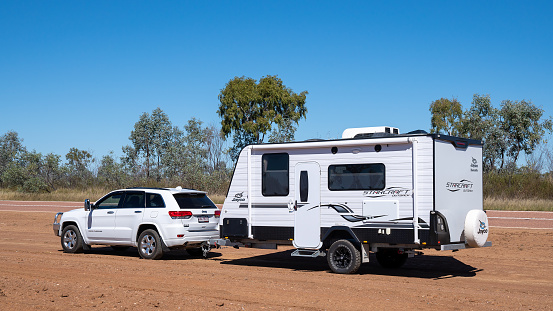 Undara to Townsville highway, Queensland, Australia - June 2020: Car and caravan parked on site of outback road amongst the dirt and dust to have a rest from driving