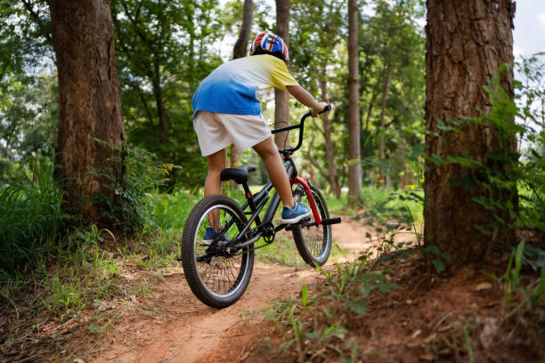 o garoto asiático está treinando para um feliz mountain bike. - pedal bicycle sports training cycling - fotografias e filmes do acervo