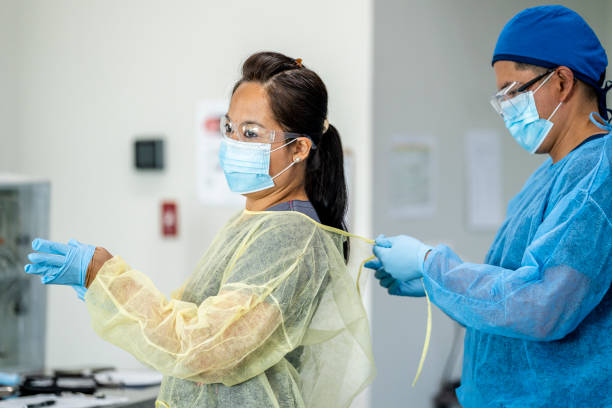 istock Two medical professionals putting on PPE (Personal Protective Equipment) 1254699507