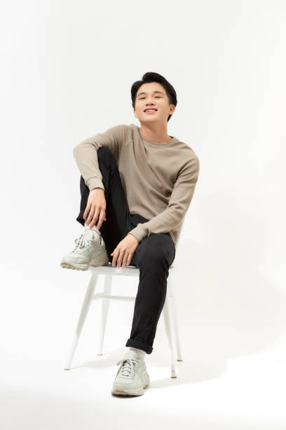 istock College age man sitting on a white chair isolated on white 1254703983
