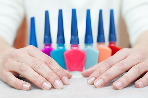 Unrecognizable woman getting ready to paint her nails with different options of nail polish