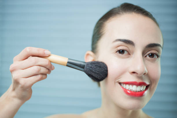 istock Beautiful young woman applying make up 1254704049
