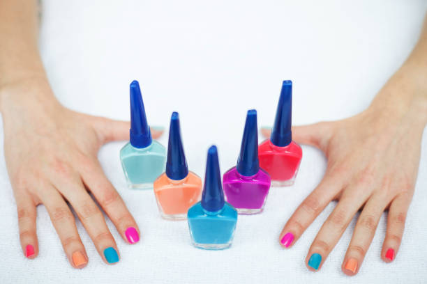 Hands of a Brazilian 45 years old woman, Caucasian, painting her nails blue, with a nail pliers and a nail polish on the table.