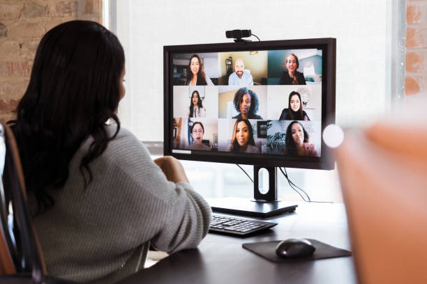 Businesswoman meets with colleagues during virtual staff meeting A group of diverse business colleagues participate in a virtual staff meeting during the COVID-19 pandemic. An African American businesswoman participates in the virtual event from her office. conference call stock pictures, royalty-free photos & images