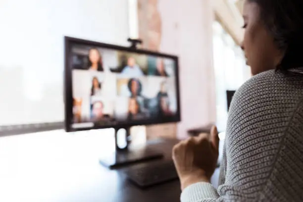 The mid adult woman video conferences with co-workers from her home office during the coronavirus shutdown.