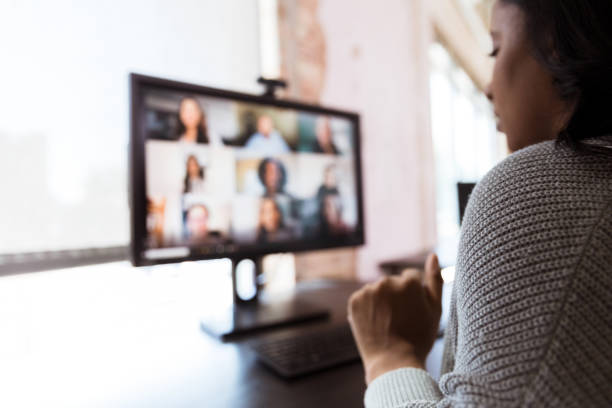 woman video conferences with co-workers during shutdown - over the shoulder view fotos imagens e fotografias de stock