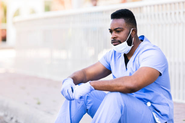 istock Male doctor, still wearing PPE, sits outside hospital after difficult shift 1254705009