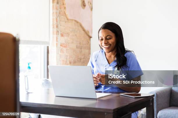 Happy Doctor Talks With Patient During Telemedicine Appointment Stock Photo - Download Image Now