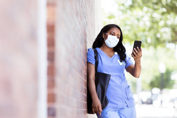 bär ansiktsmask på grund av covid-19, tar sjuksköterska selfie - nurse on phone serious bildbanksfoton och bilder