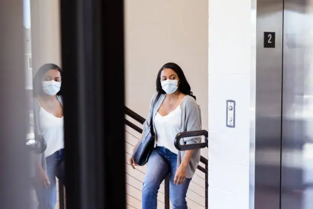 After the doctor's office opened up during the coronavirus epidemic, a woman wearing a protective mask goes up the stairs of the building to her appointment.