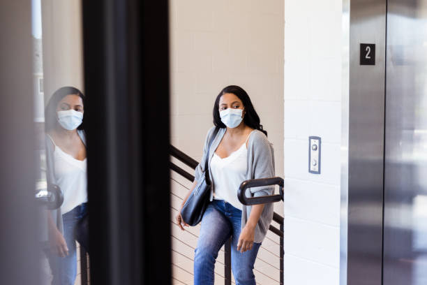 woman wearing mask goes upstairs to doctor's office - upstairs imagens e fotografias de stock
